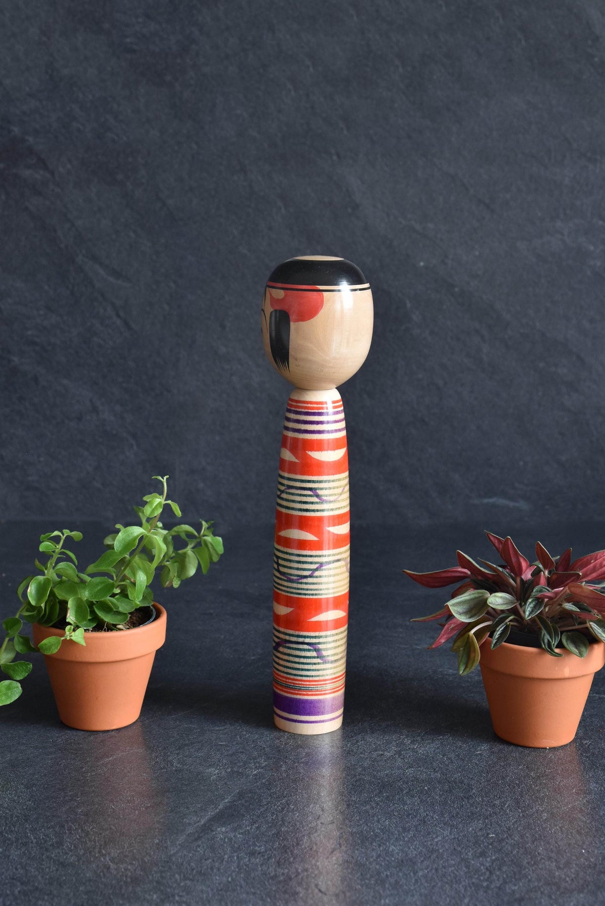 Tsuchiyu kokeshi doll featuring slender body and vibrant red and green lathe-spun bands