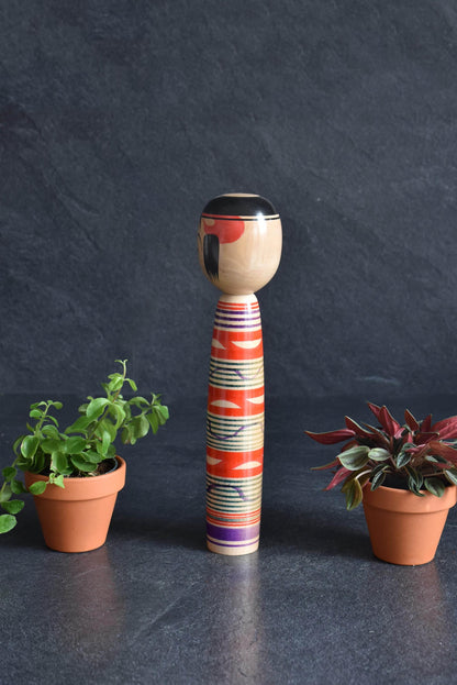 Tsuchiyu kokeshi doll featuring slender body and vibrant red and green lathe-spun bands