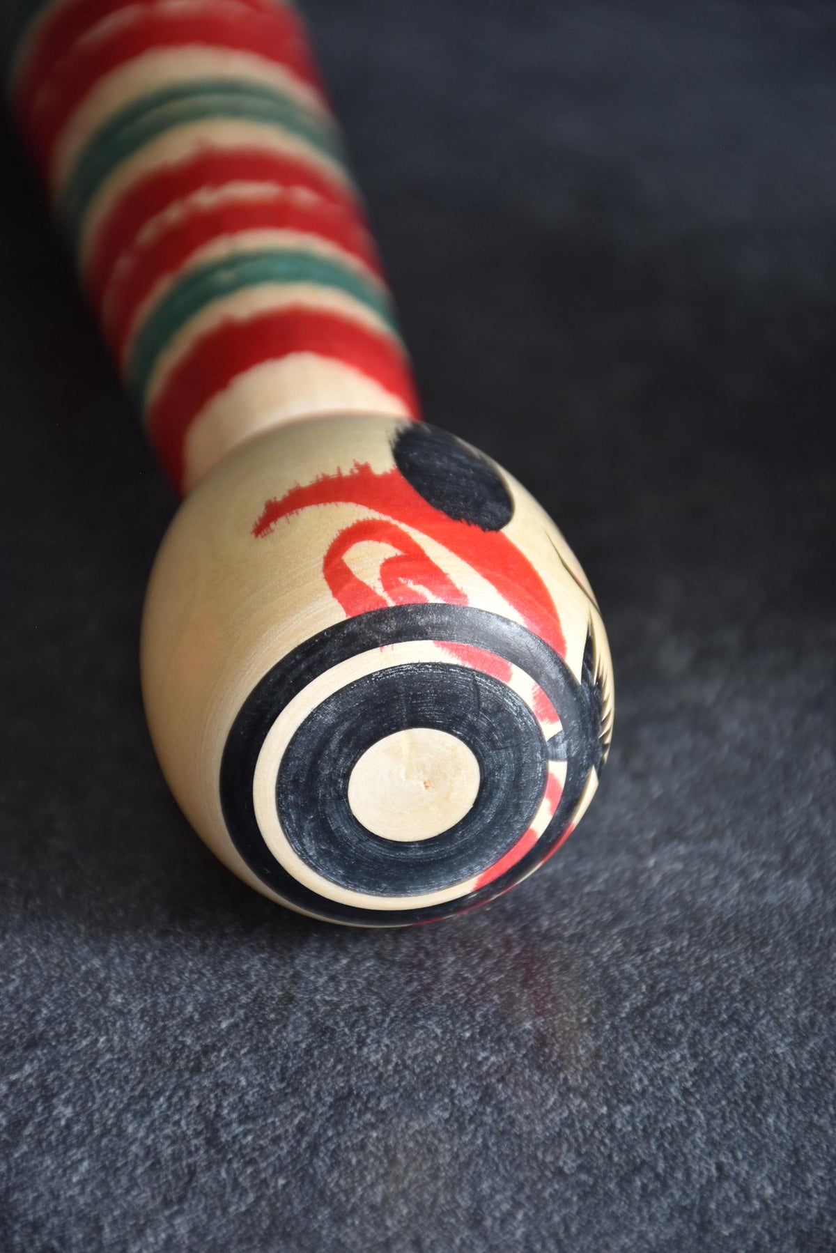 Tsuchiyu-Kei kokeshi top head angle showing black concentric circle pattern and facial painting