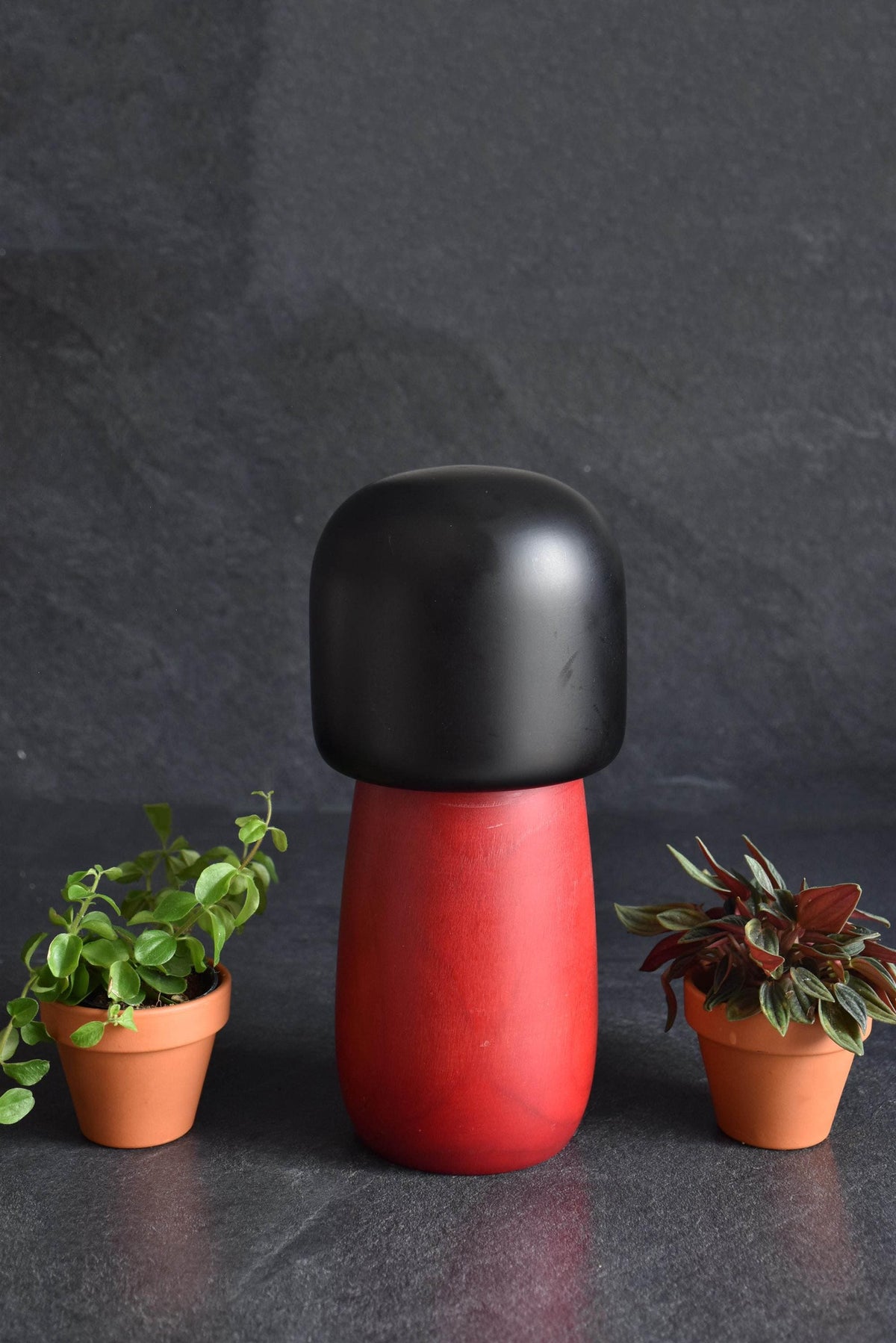 Masae Fujikawa kokeshi doll side profile showing the rounded black head and red kimono body