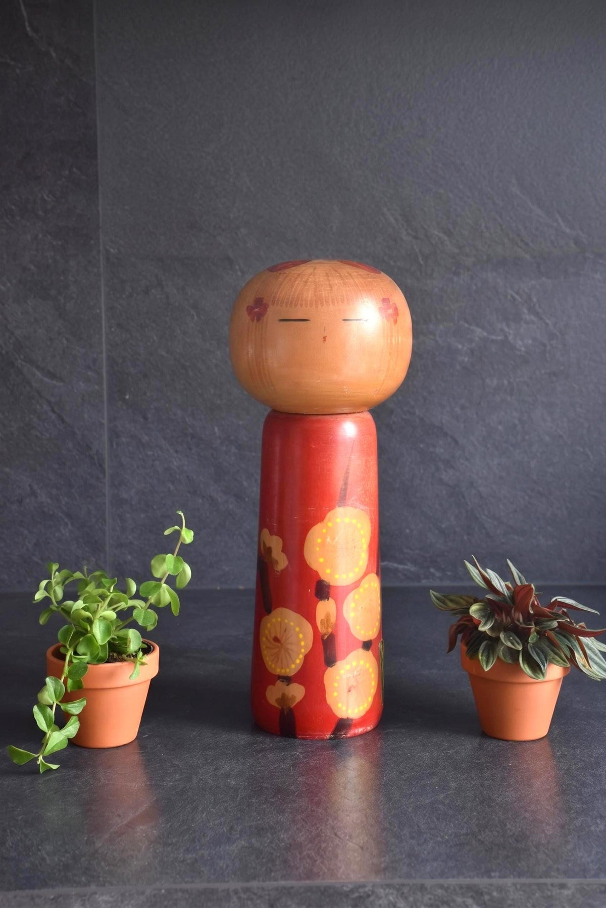 Hakuho Sosaku Kokeshi Plum Blossom Red Doll featuring a painted face and floral hair ornaments on a red body with ume
