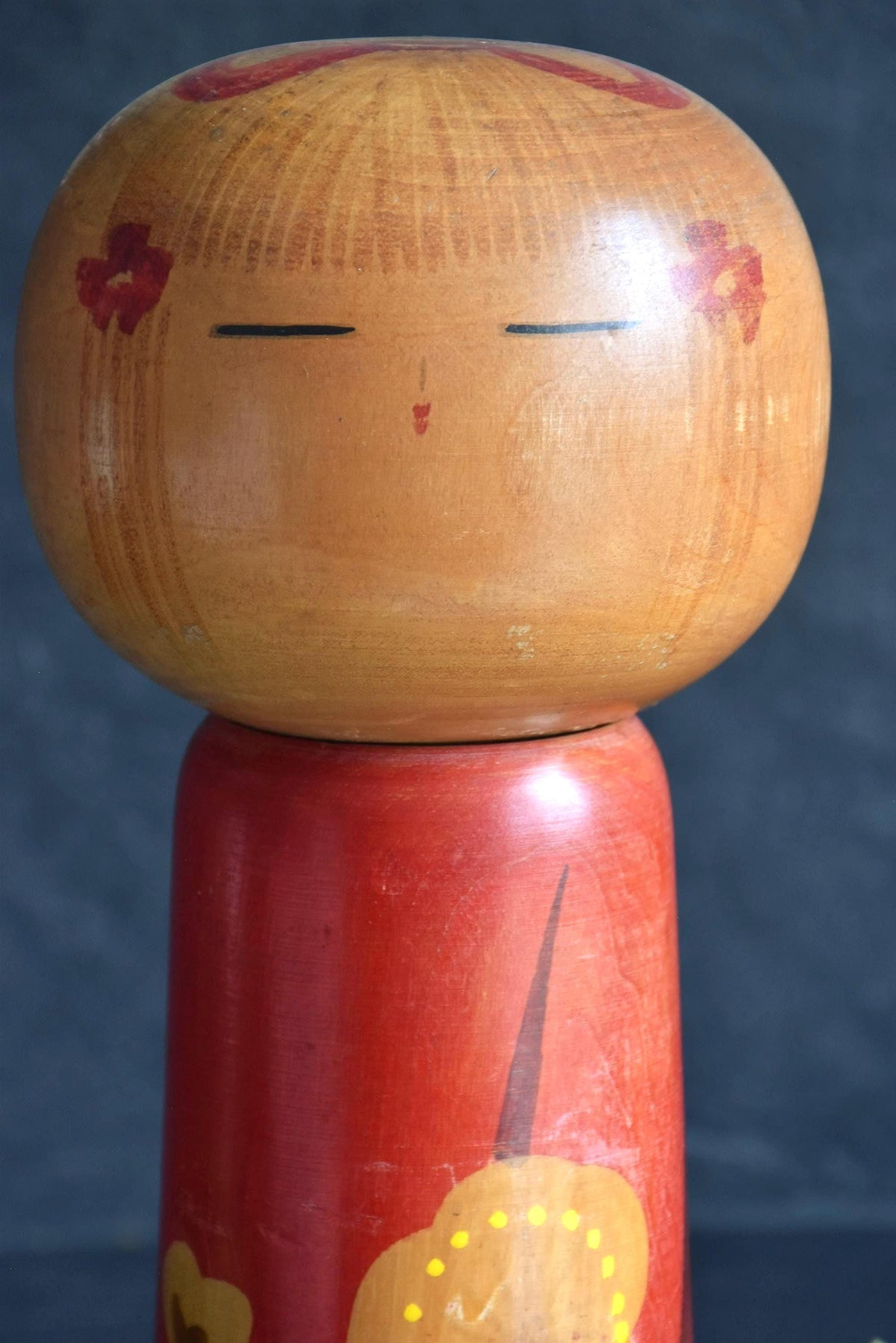 Hakuho Sosaku Kokeshi doll face close-up showing the serene painted expression, closed eyes, and delicate floral hair