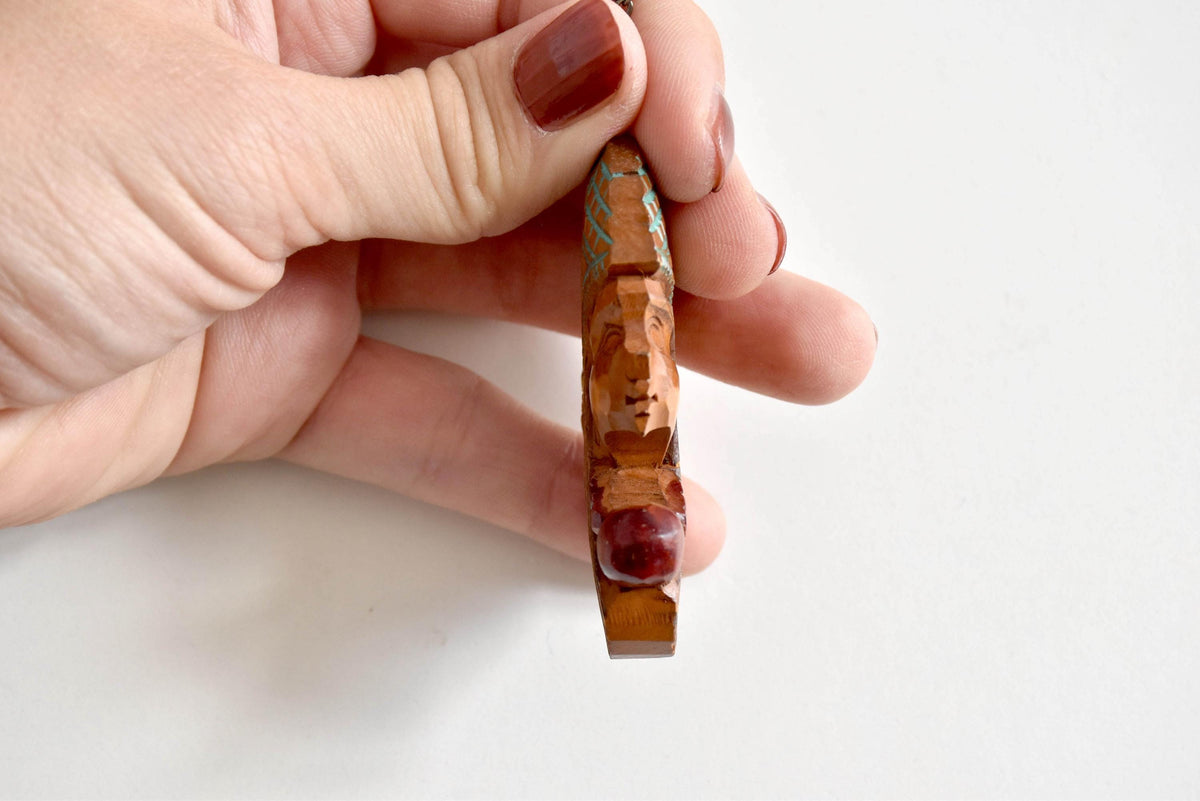 Ainu double-sided wooden pendant necklace viewed from the side profile highlighting the carved wooden edge