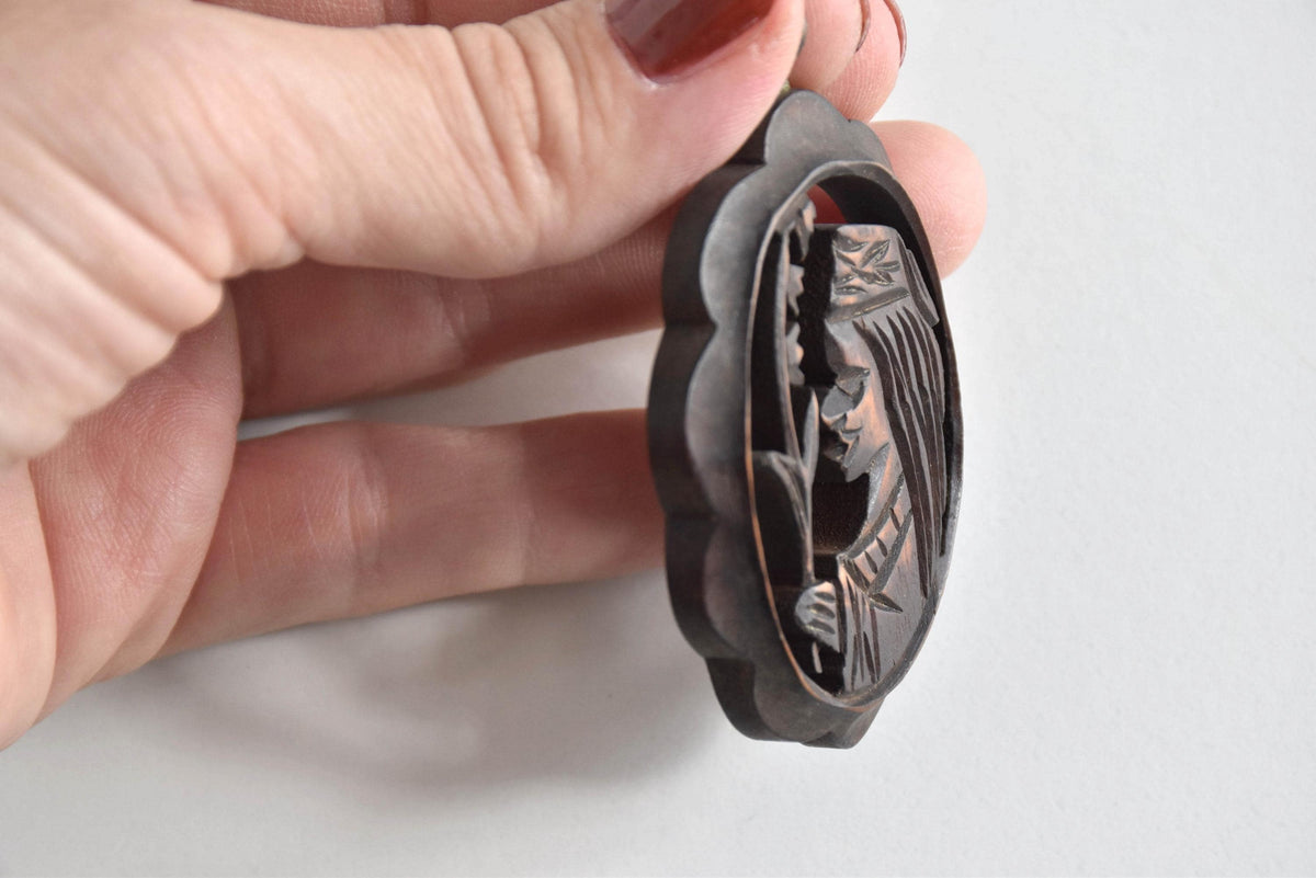 Ainu wooden pendant necklace profile view showing the thickness of the carved wood frame