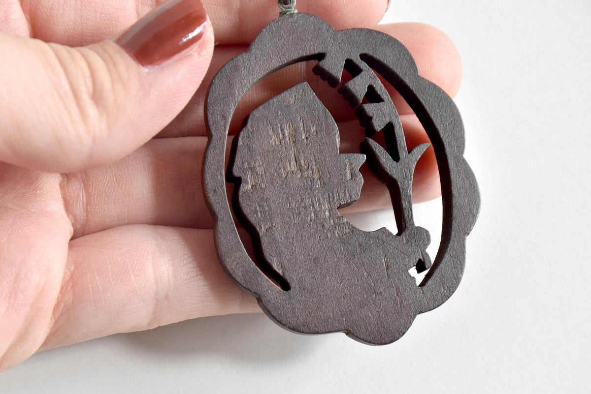 Ainu wooden pendant necklace back view showing the reverse of the carved wooden figure