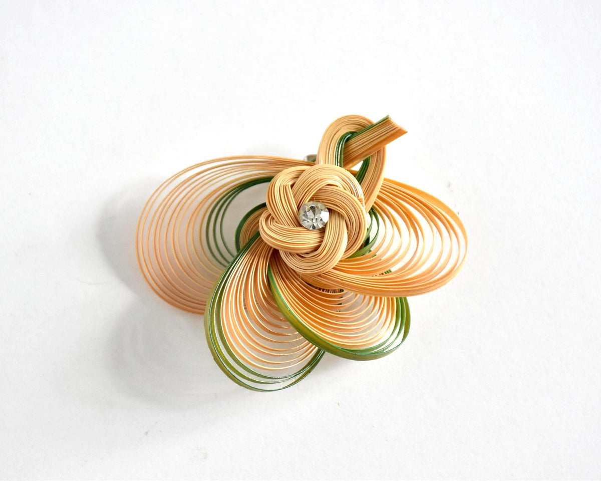 Hand-Woven Bamboo Knot Brooch In Beige And Green on a plain white surface