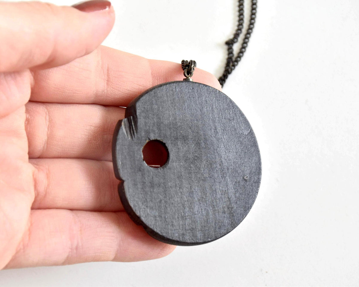 Ainu hand-carved wooden floral medallion necklace back view in hand