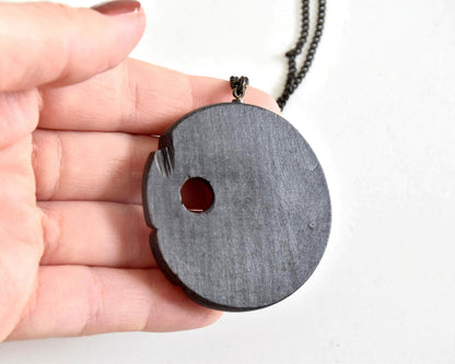 Ainu hand-carved wooden floral medallion necklace back view in hand