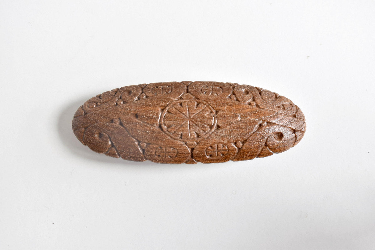 Ainu wooden hair barrette showing top view of the carved geometric and nature-inspired motifs