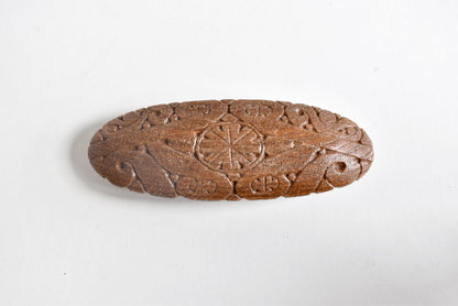 Ainu wooden hair barrette showing top view of the carved geometric and nature-inspired motifs