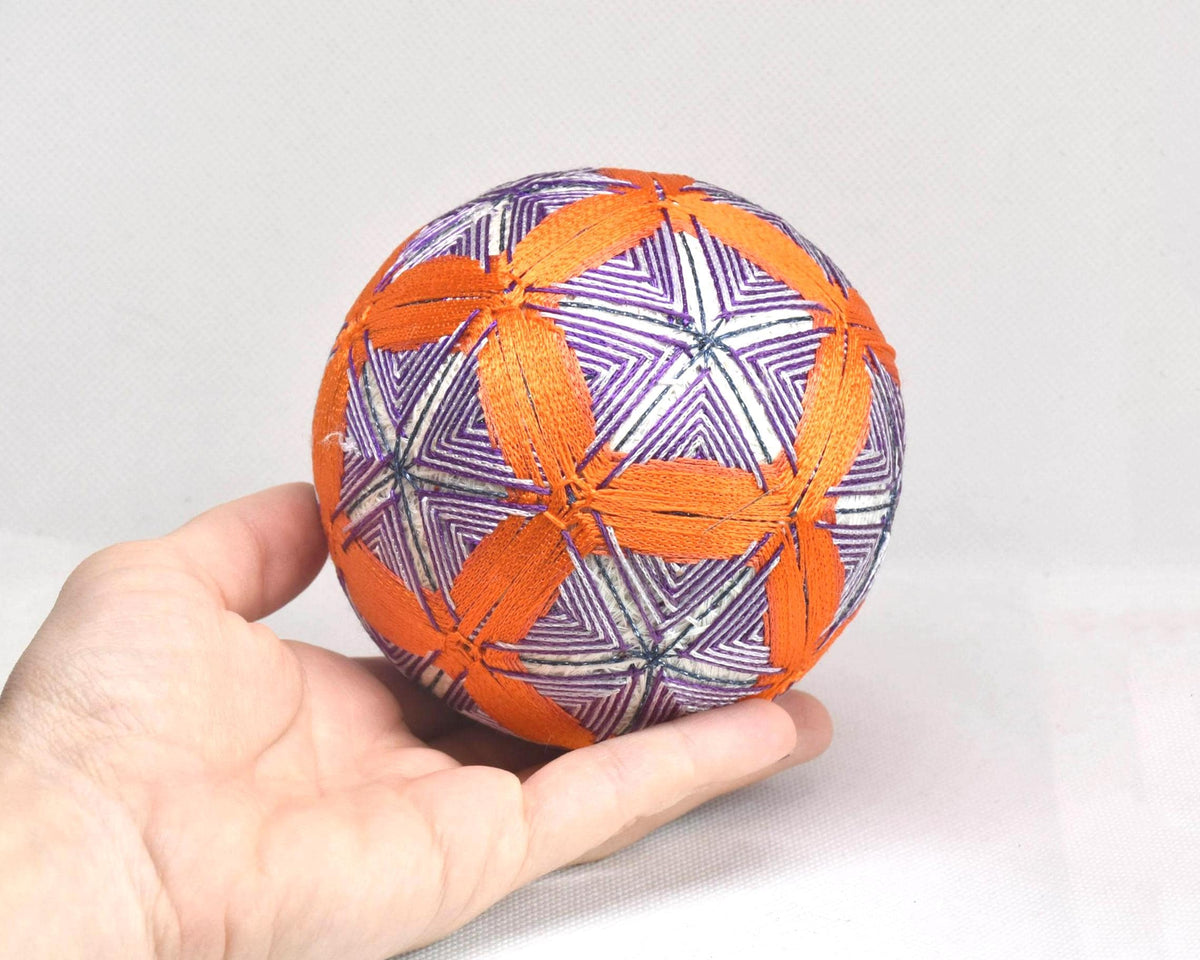 Hand-Embroidered Temari Ball Orange And Purple table scatter resting on an open palm