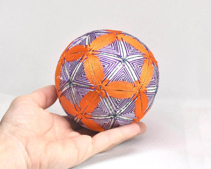 Hand-Embroidered Temari Ball Orange And Purple table scatter resting on an open palm