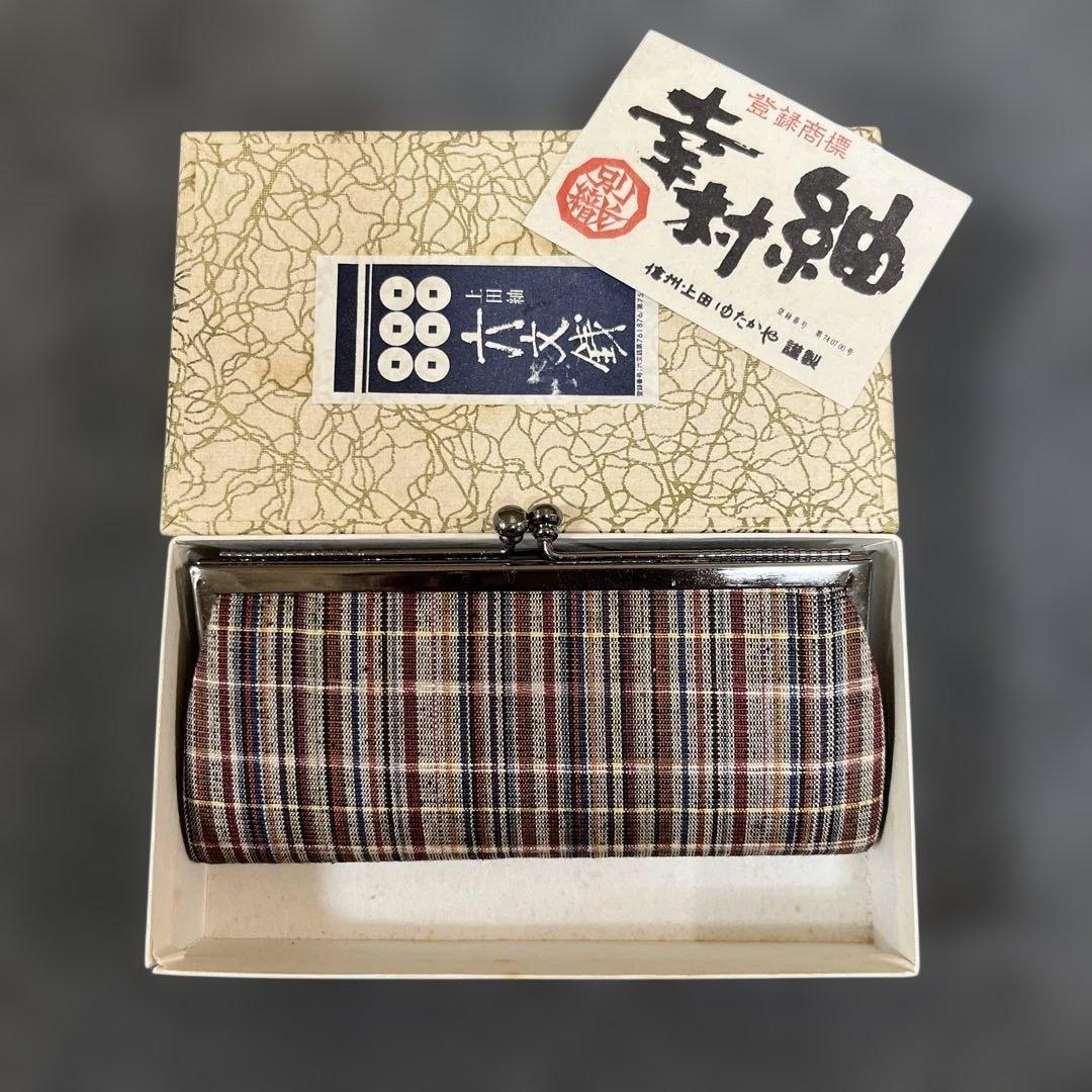 Ueda Tsumugi silk coin purse shown resting inside its original storage box with leaflet