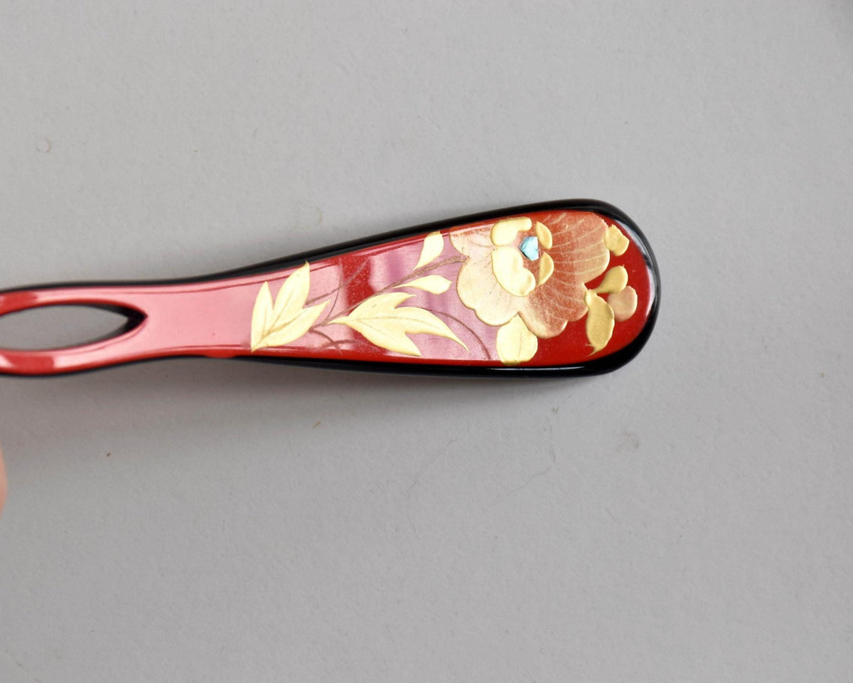 Red lacquered kanzashi hair accessory close up of the floral motif