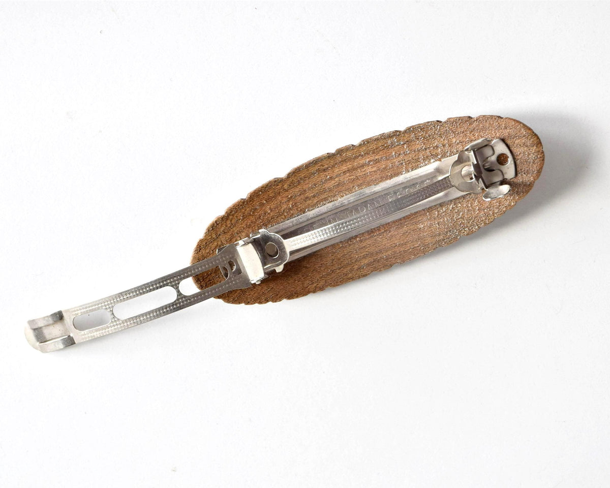 Ainu wooden hair barrette showing the metal clasp fully extended in the open position