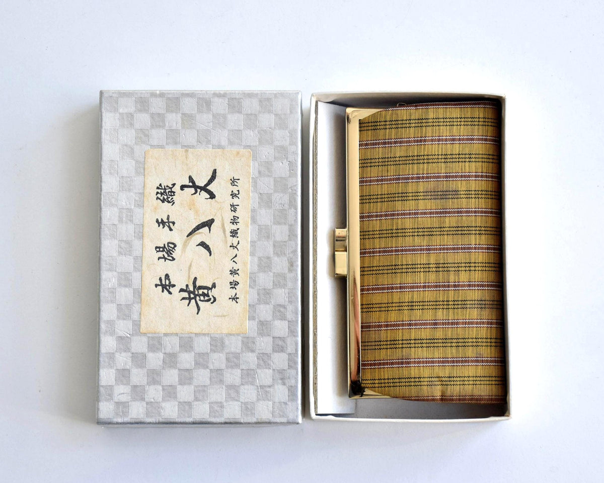 Kihachijo silk coin purse resting in box next to lid with Japanese textile label