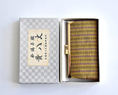 Kihachijo silk coin purse resting in box next to lid with Japanese textile label
