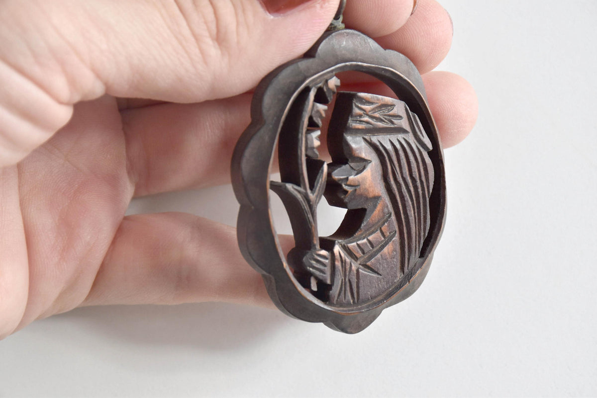 Ainu wooden pendant necklace side angle showing the openwork figure carving depth