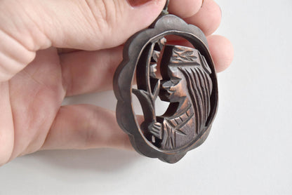 Ainu wooden pendant necklace side angle showing the openwork figure carving depth