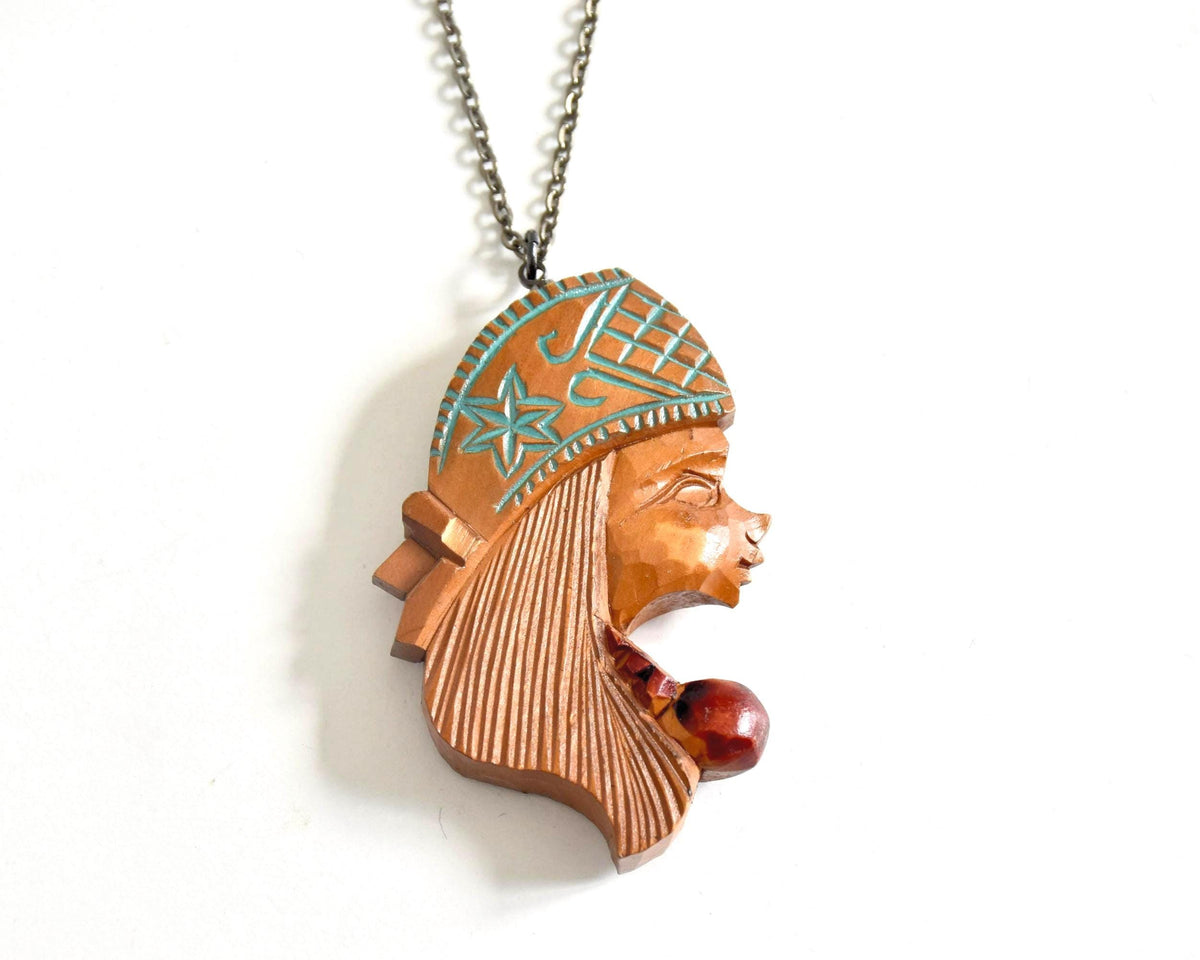 Ainu double-sided wooden pendant necklace showing the reverse female face profile with detailed carved headpiece