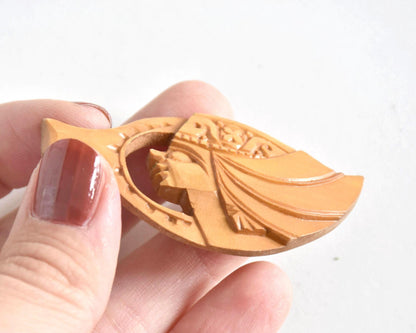 Ainu hand-carved wooden brooch viewed from an angle in a hand