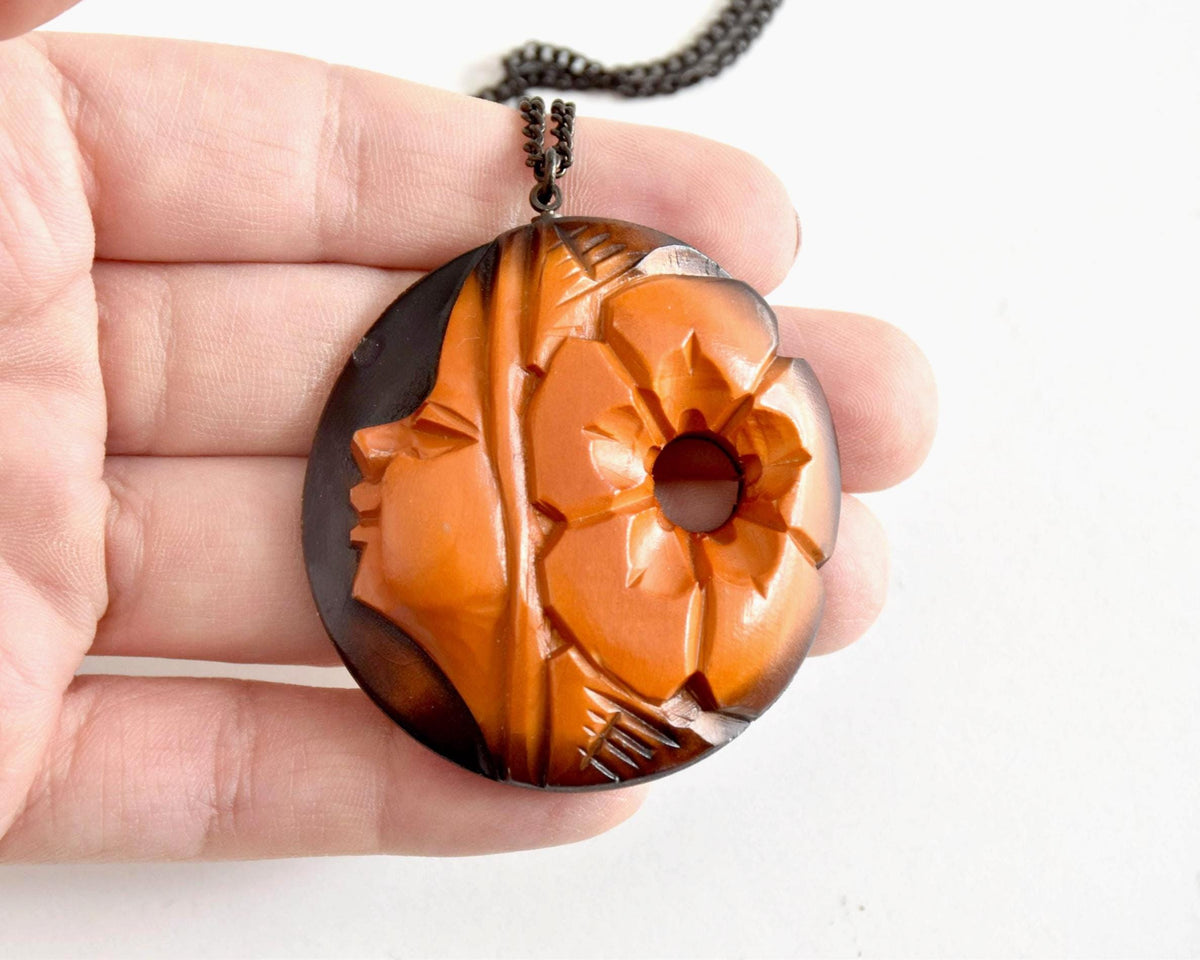 Ainu hand-carved wooden floral medallion necklace closeup in hand