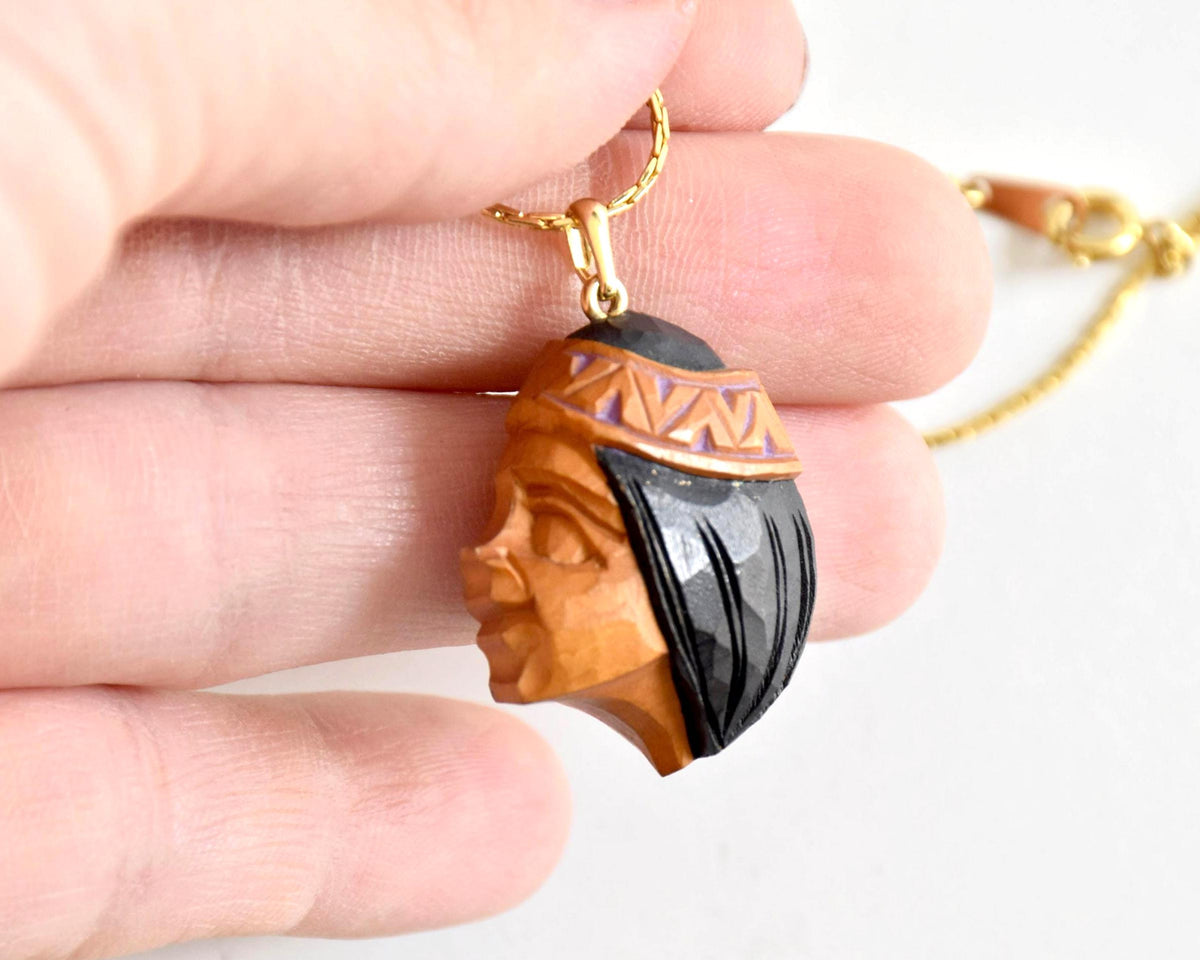 Ainu handcarved wood pendant necklace held in hand for scale