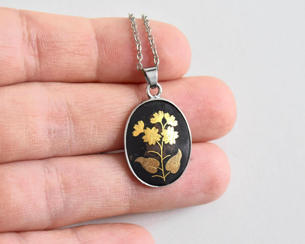 Japanese Zogan Floral Pendant Gold Inlay Damascene necklace held in a hand