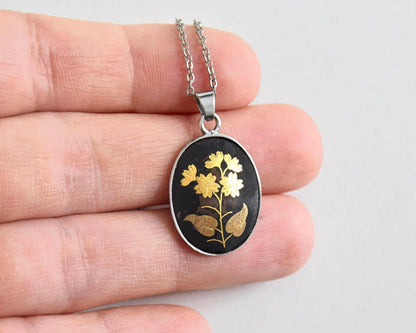 Japanese Zogan Floral Pendant Gold Inlay Damascene necklace held in a hand