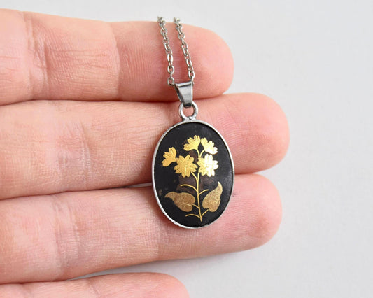 Japanese Zogan Floral Pendant Gold Inlay Damascene necklace held in a hand