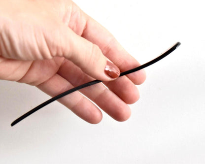 Red lacquered kanzashi hair accessory shown in profile curved shape held in hand