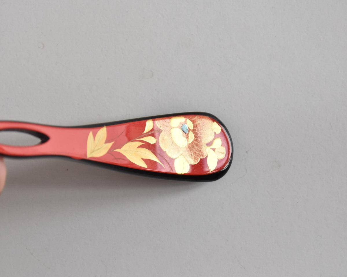 Red lacquered kanzashi hair accessory angled close up of the floral maki-e