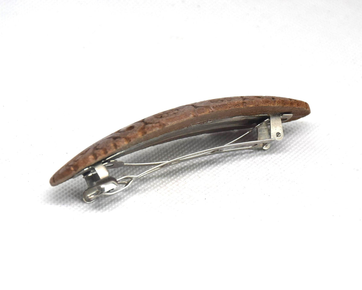 Ainu wooden hair barrette viewed from the side showing the curved shape and attached clasp