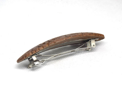 Ainu wooden hair barrette viewed from the side showing the curved shape and attached clasp