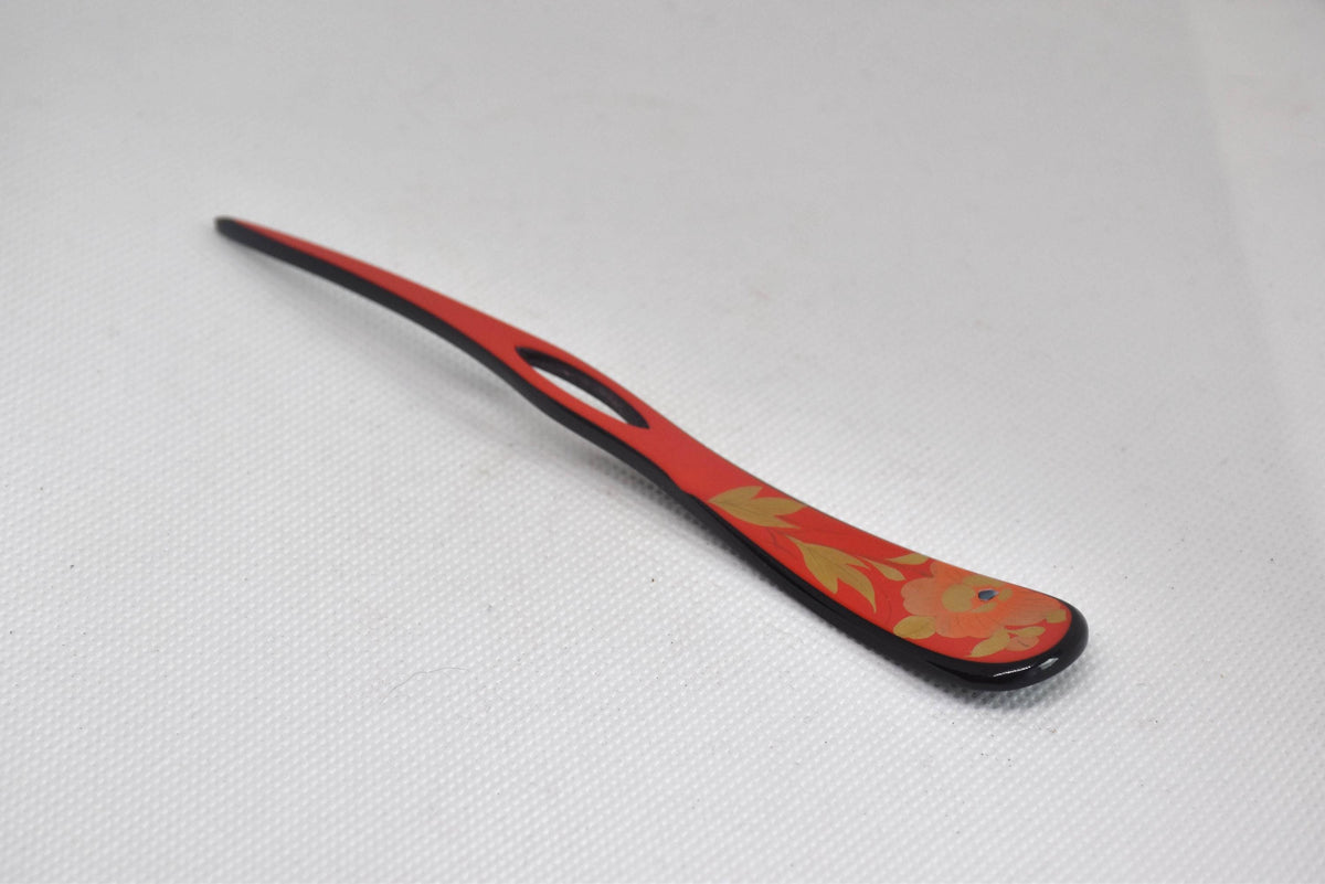 Red lacquered kanzashi hair accessory angled view showing the cutout prong