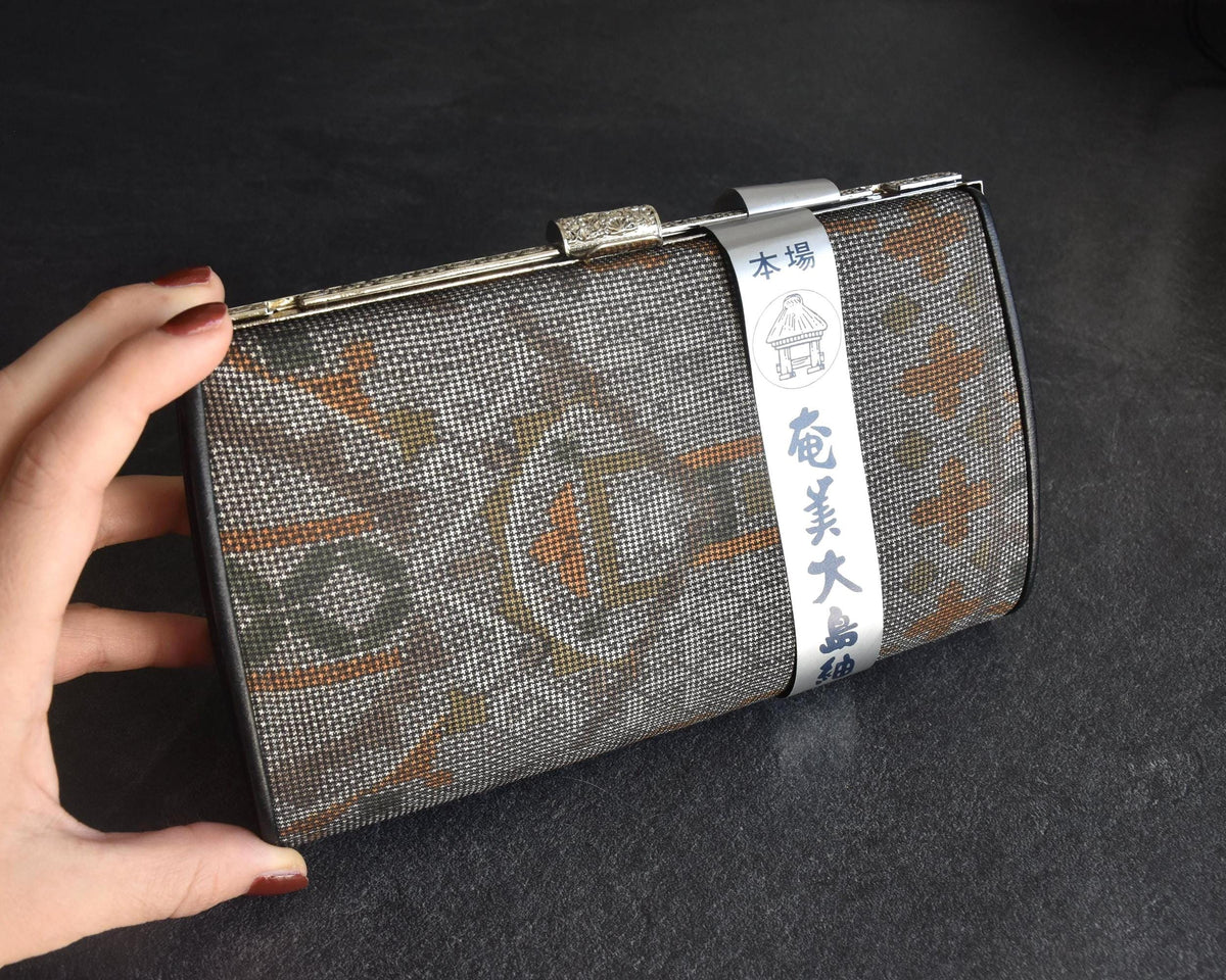Amami Oshima Tsumugi silk clutch shown in hand to display scale