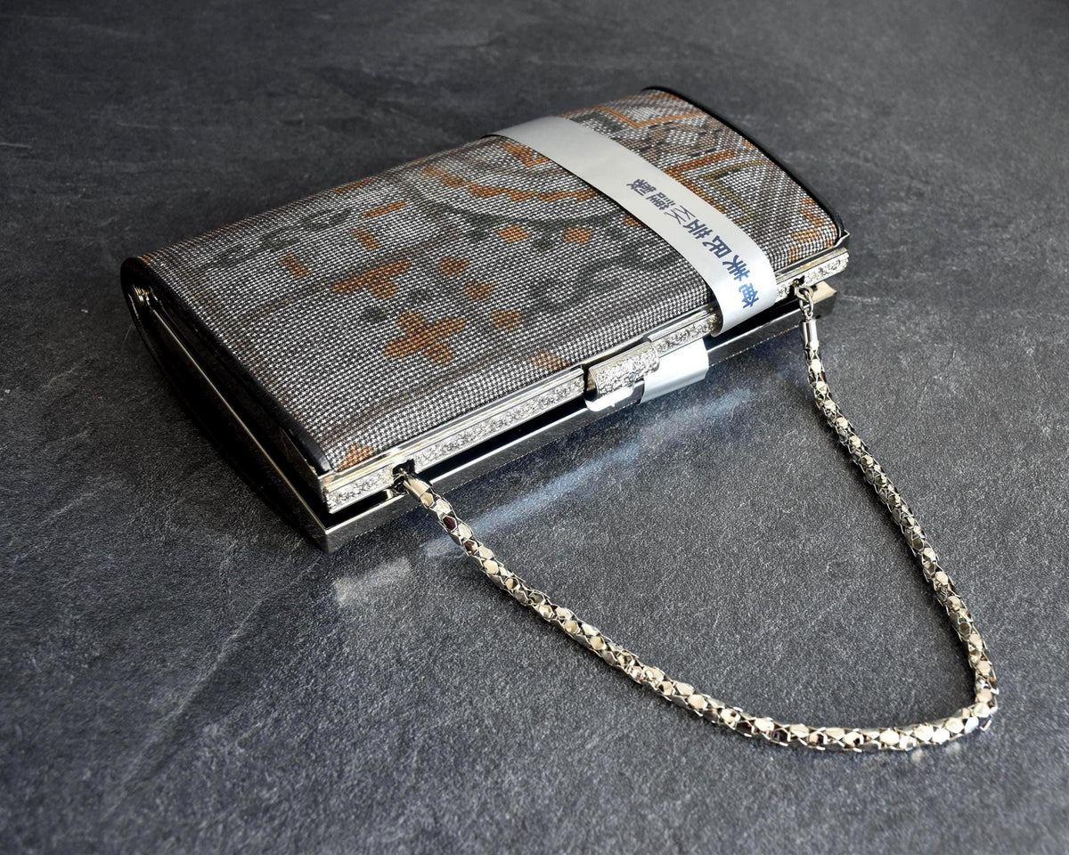 Amami Oshima Tsumugi silk clutch angled view showing metallic chain strap
