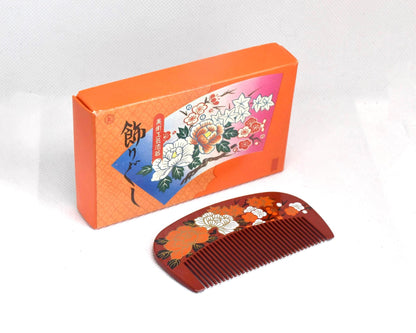 Toyama Urushi Kushi Comb With Peony And Plum Motif next to its original orange presentation box