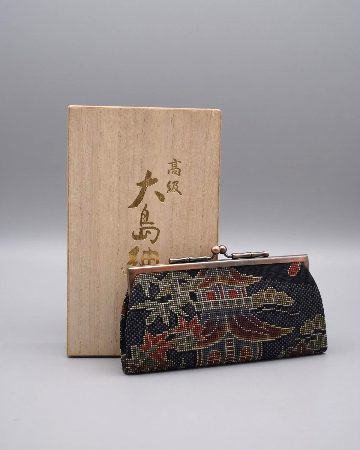 Blue Oshima Tsumugi Silk Gamaguchi Coin Purse with traditional wooden storage box displaying Japanese characters