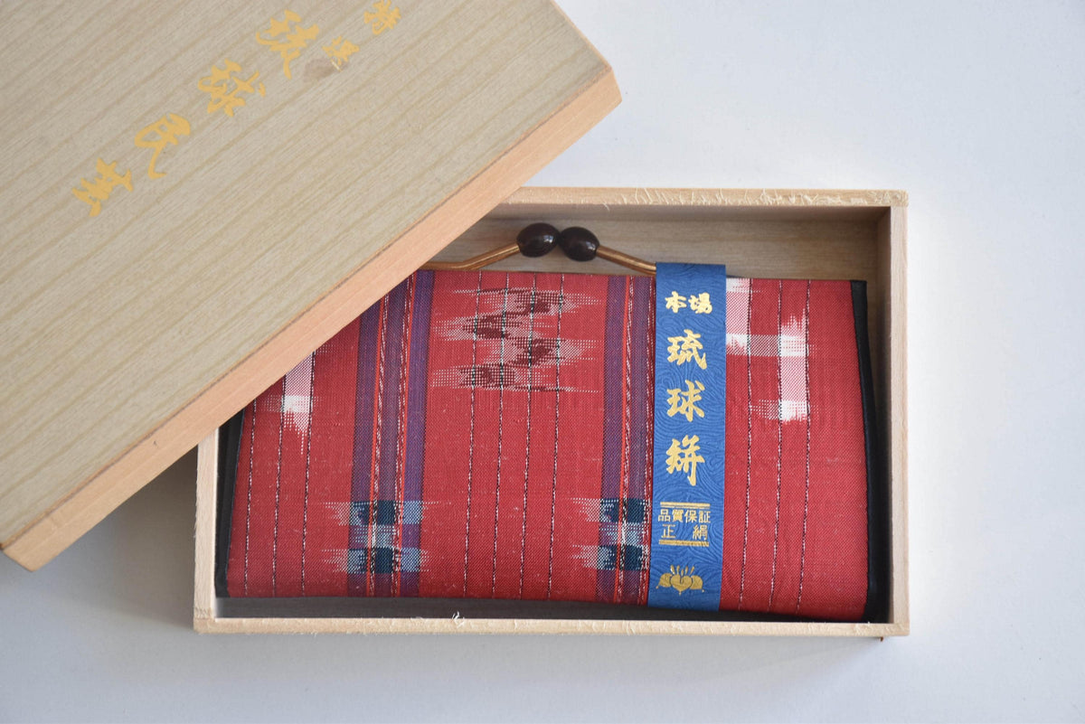 Ryukyu Kasuri Geometric Ikat Silk Wallet Red placed neatly inside the wooden box