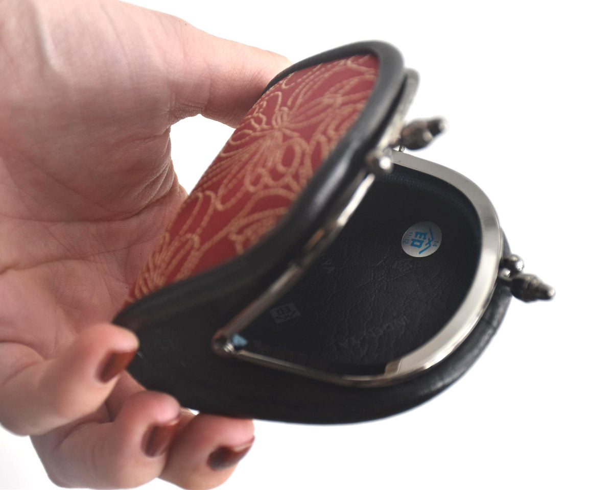 Inden deerskin coin purse held open displaying the interior lining with Japanese maker sticker