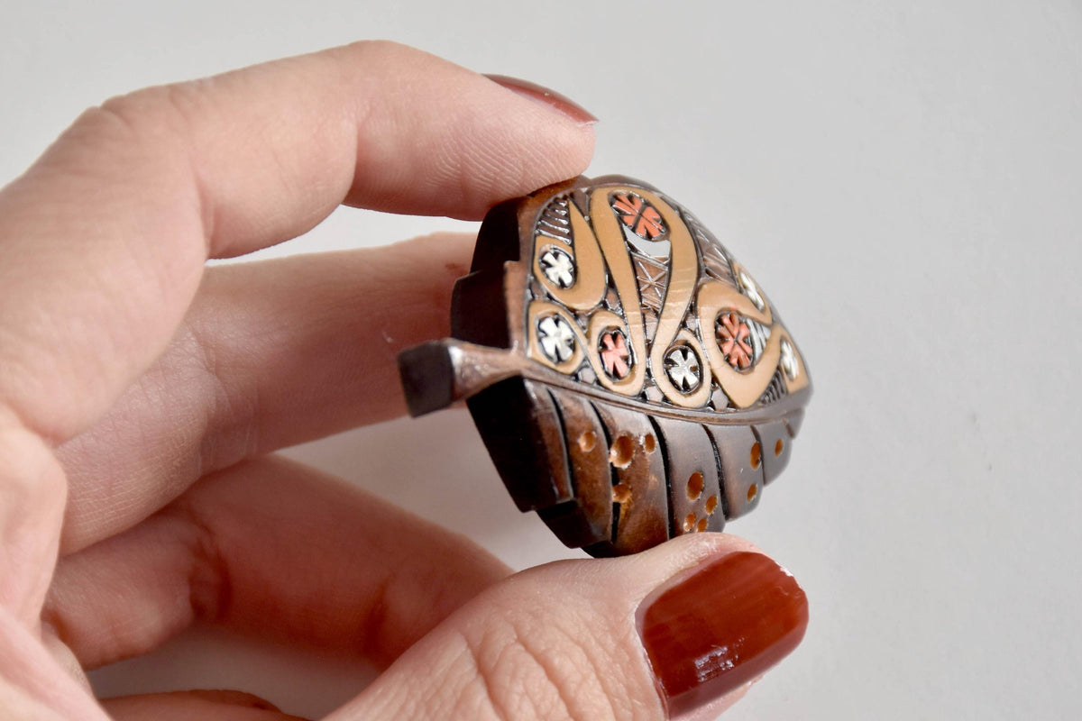 Front edge angle of Ainu leaf brooch held in hand showing carved relief