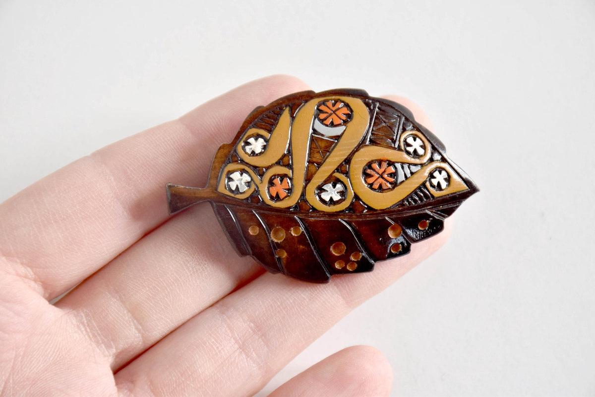 Ainu leaf brooch held in a hand to demonstrate its size and details