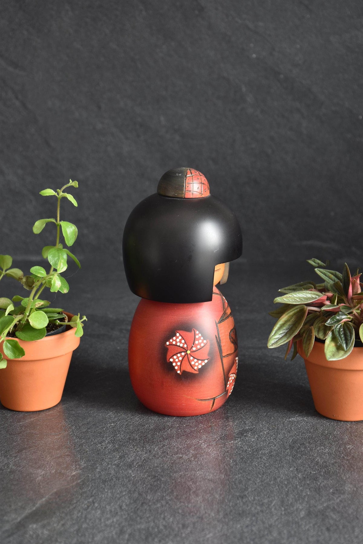 Masae Fujikawa kokeshi doll showing side view of red kimono and floral carving