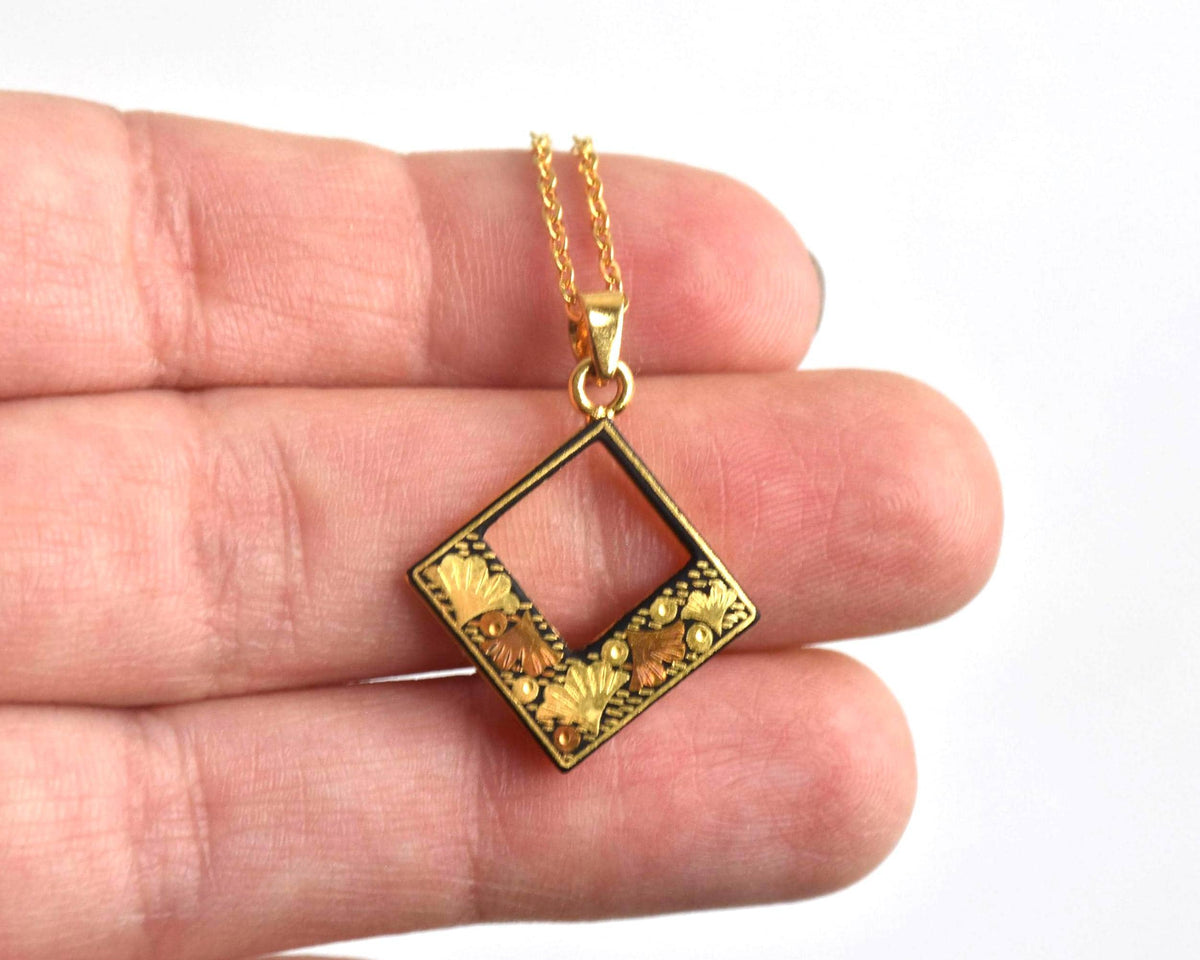 Floral Zogan Damascene Inlay Gold Necklace pendant shown held on a hand for scale