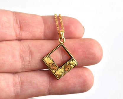 Floral Zogan Damascene Inlay Gold Necklace pendant shown held on a hand for scale