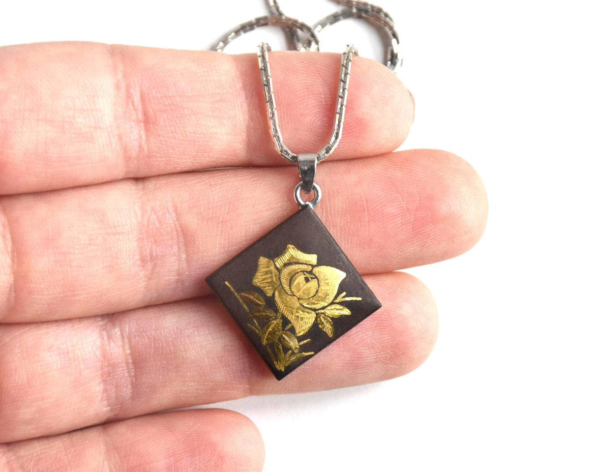 Japanese Zogan Floral Damascene Pendant Necklace held in palm for scale comparison