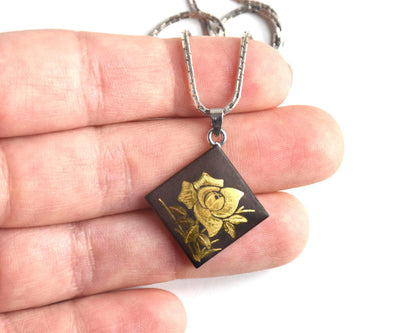 Japanese Zogan Floral Damascene Pendant Necklace held in palm for scale comparison