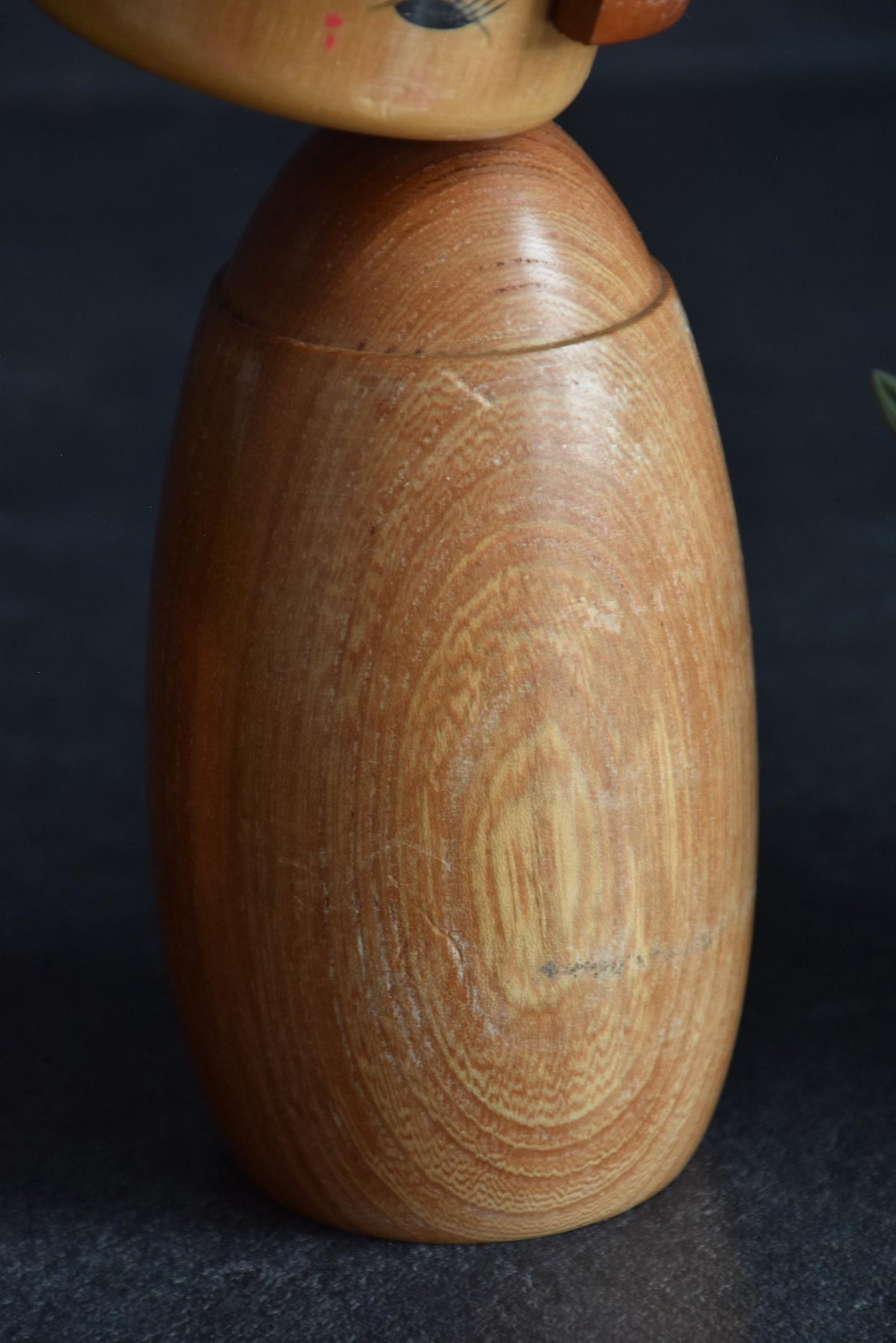 Masuo Sato kokeshi doll close-up showing texture and grain of the wooden body