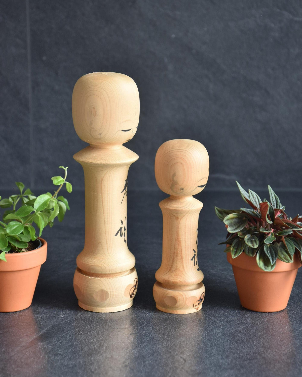Isamu Ise kokeshi dolls angled side view featuring painted faces and kanji.